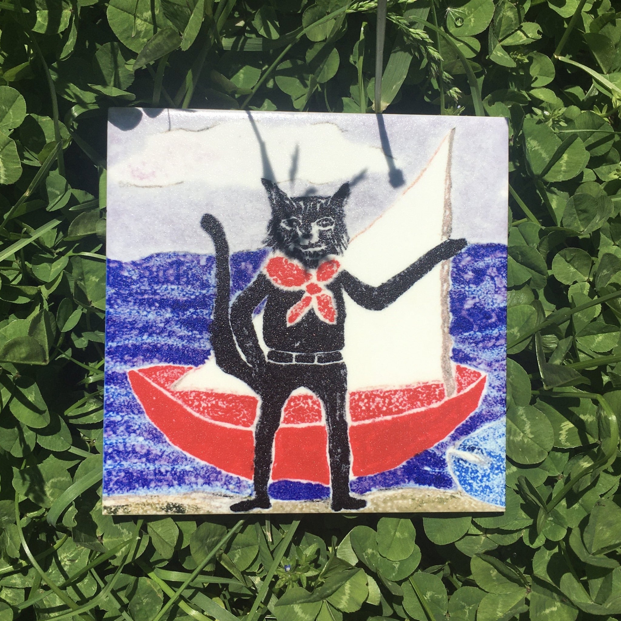 Ceramic tile coaster. Cat and sailboat. Top image. Vitrene by Christine and Bruce Green. Pottery and artwork from Micanopy Florida.